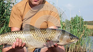 Success carp fishing. Happy fisherman with big fish trophy in hands