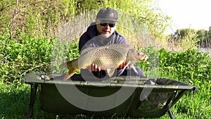 Success carp fishing. Man showing big carp in his hands