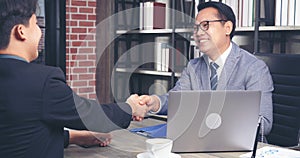 Success collaboration partners sign contract and shake hands after success business joint venture deal. Diversity Businessman