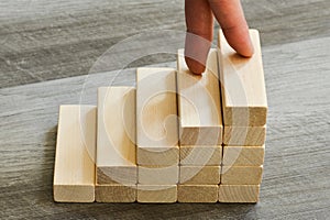 Success Concept - Fingers Climbing Up To Top Of Stairway Over Dark Wooden Background