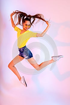 Success, dream, femenine girlish life concept. Excited brunette lady model is jumping up, wearing casual clothes, white