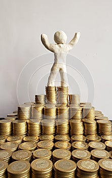 success and economic growth, a human figure of white plasticine and stacked coins of mexican pesos