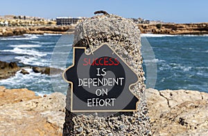 Success and effort symbol. Concept words Success is dependent on effort on beautiful black chalkboard. Beautiful stone sea