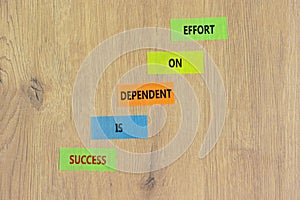 Success and effort symbol. Concept words Success is dependent on effort on colored paper. Beautiful wooden table wooden background