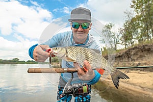 Success fishing. Fisherman with chub fish at wild river