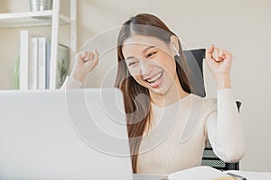 Success, happy asian young business woman wearing earphones, listen to test exam winner in class study of college, celebrate