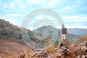 Success Hiker man standing  on the top mountain with walking pole after hiking to goal . achievement adventure