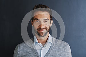 Success makes me smile. Portrait of a handsome young businessman posing against a dark background.