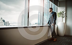 Success minded people create success. a young businessman looking thoughtfully out of an office window.