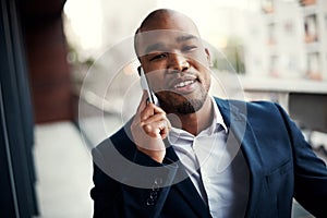 Success requires one to be mobile. Portrait of a handsome young businessman talking on a cellphone outside his office.