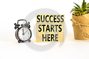 Success starts here symbol. Concept word Success starts here on beautiful wooden block. Black alarm clock. Beautiful white