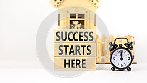 Success starts here symbol. Concept word Success starts here on beautiful wooden block. Black alarm clock. Beautiful white