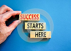 Success starts here symbol. Concept word Success starts here on beautiful wooden block. Businessman hand. Beautiful blue