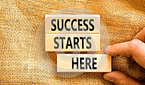 Success starts here symbol. Concept word Success starts here on beautiful wooden block. Businessman hand. Beautiful canvas