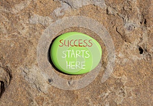 Success starts here symbol. Concept word Success starts here on beautiful big green stone. Beautiful brown stone background.