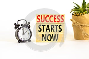 Success starts now symbol. Concept word Success starts now on beautiful wooden block. Black alarm clock. Beautiful white