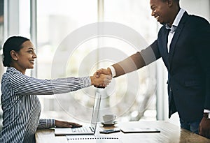 Success starts by working with the right people. two businesspeople shaking hands in an office.