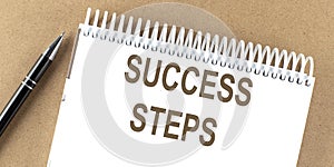 SUCCESS STEPS text on a notepad with pen, business