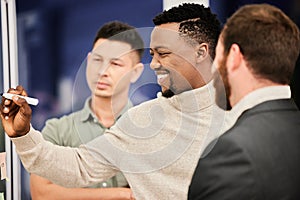 Success is in the strategy. three handsome businessmen working on a glass wipe board during a meeting in the boardroom.