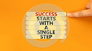 Success symbol. Concept words Success starts with a single step on wooden stick. Beautiful orange background. Businessman hand.