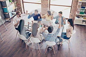 Success and team work concept. Top up of team of business partners with raised up hands in light modern workstation, celebrating