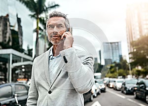 Success was destined for him. a mature businessman talking on a cellphone in the city.