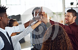 Success will be ours as a team. a group of businesspeople high fiving together in an office.