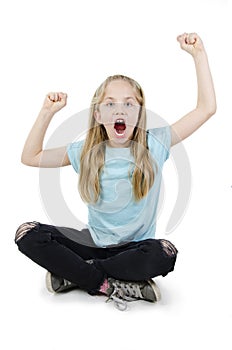 Success young girl celebrating sitting on floor. Cheering teenage girl. Portrait of beautiful energetic girl with arms raised.