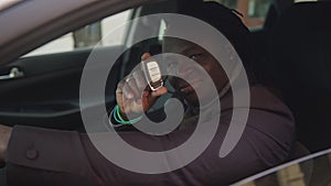 Successful african american black man showing car key while sitting in his new car