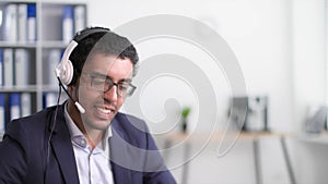 successful african american businessman rejoices at good idea while working at computer and talking to a client using a