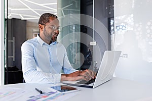 Successful african american businessman working inside office with laptop, man smiling and happy with achievement result