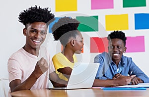 Successful african american male student at computer with group of students