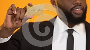 Successful African-American oligarch holding golden credit card rich people life