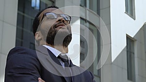 Successful afro-american businessman standing near office building, closeup