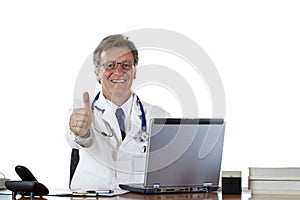 Successful aged doctor at desk holding thumb up