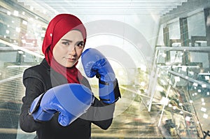 Successful and aggressive young muslimah businesswomen with boxing glove over abstract double exposure background
