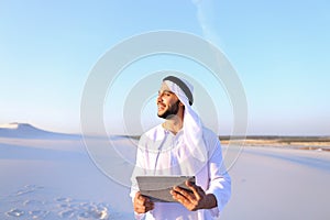 Successful Arabian businessman holds in hands and uses tablet, s
