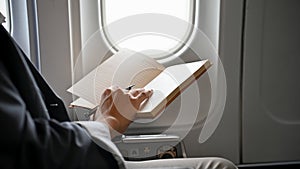 Successful Asian businessman reading a book during the flight for his business trip