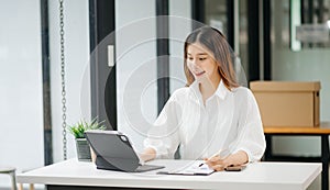 Successful Asian Businesswoman Analyzing Finance on Tablet and Laptop at modern Office Desk tax, report, accounting, statistics,