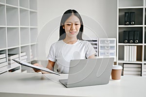 Successful Asian Businesswoman Analyzing Finance on Tablet and Laptop at Office Desk tax, report, accounting, statistics, and
