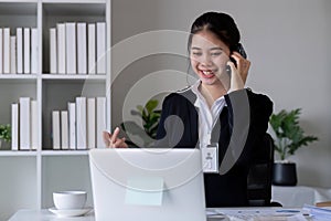 Successful Asian businesswoman sitting in modern office Use a calculator and laptop to calculate tax and finance.