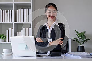 Successful Asian businesswoman sitting in modern office Use a calculator and laptop to calculate tax and finance.