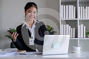 Successful Asian businesswoman sitting in modern office Use a calculator and laptop to calculate tax and finance.