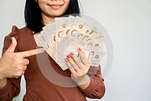 Successful Asian woman hand showing Thai money banknotes ,investment and earning conce