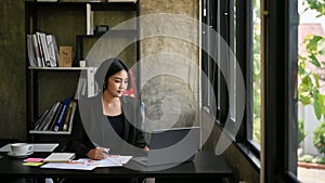 Successful Asian businesswoman focuses on her work on her laptop in the office