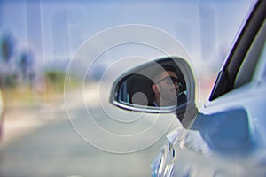 Successful, attractive, young Hispanic man in jacket and sunglasses reflected in the mirror of his white luxury car. Concept, cars