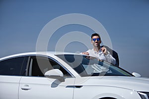 Successful, attractive, young Hispanic man, with white shirt and jacket over his shoulder and sunglasses, leaning on the roof of