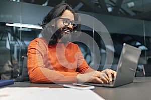 Successful bearded indian guy project manager sitting at workdesk