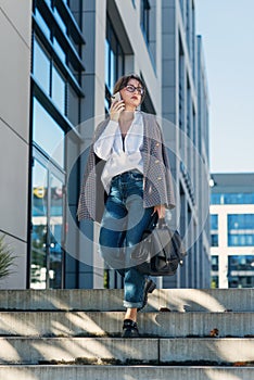 Successful beautiful business woman in suit with document walking to the meeting near modern office building.