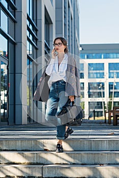 Successful beautiful business woman in suit with document walking to the meeting near modern office building.